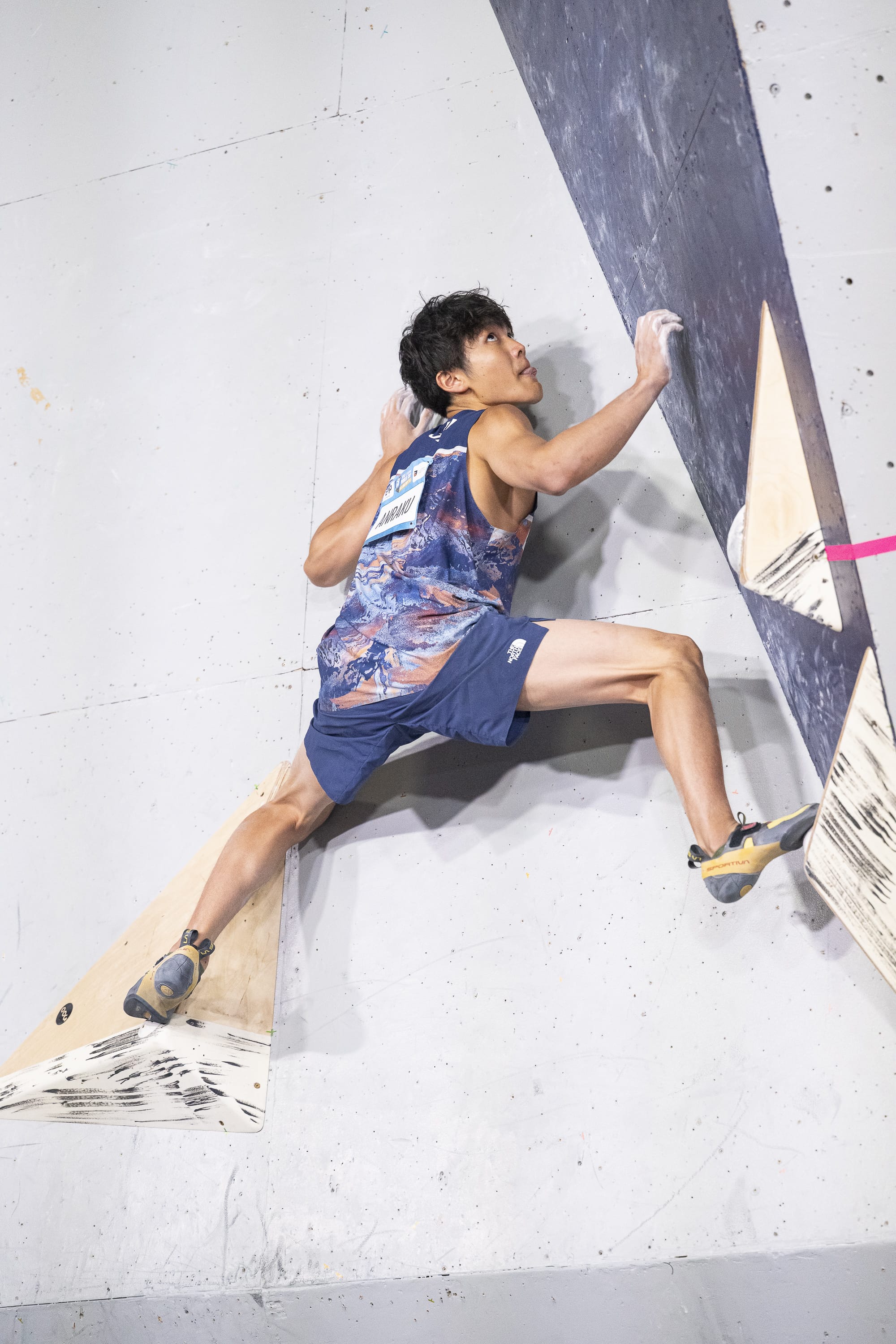 Sorato Anraku with his tongue out setting up to top the slab boulder in the final